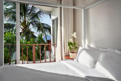 a bedroom with a white bed and a balcony at Villa Nalinnadda Petite Hotel & Spa, Adults Only - SHA Extra Plus in Lamai