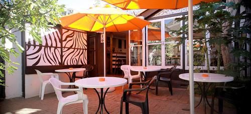 a patio area with tables, chairs and umbrellas at Zebra Crossing Backpacker in Cape Town