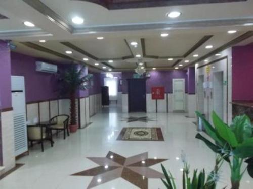 Habitación con paredes moradas y pasillo con mesas y sillas. en Arabian Palm Hotel, en Rabigh