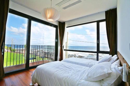 a bedroom with two beds and a large window at The Villas Ocean for Family in Seogwipo