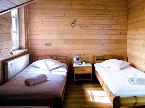 two beds in a room with wooden walls at Homestead Sartakampis in Gipenai