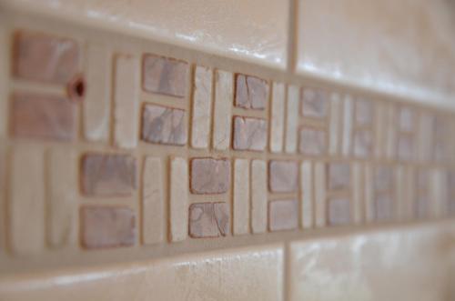 a white tile wall with a pattern on it at Apartment Paradise - GRIWA RENT AG in Grindelwald