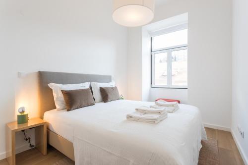 una camera da letto con un letto bianco e asciugamani di FLH Restauradores Charming Apartment a Lisbona