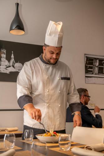 a chef preparing a bowl of food in a kitchen at Hotel Casa Del Pellegrino in Padova