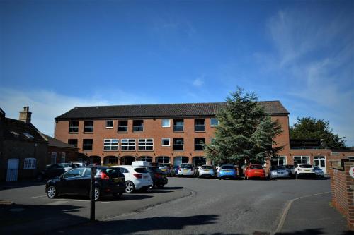 a parking lot with cars parked in front of a building at Oliver Cromwell Hotel in March