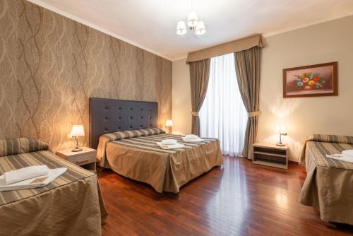 a hotel room with two beds and a window at Dreams Roma B&B in Rome