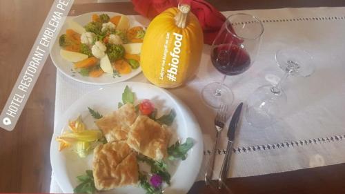 a table with two plates of food and glasses of wine at Hotel Restaurant Emblema in Petrelë
