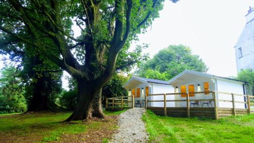 uma casa branca com uma árvore em frente em Dunmore Gardens Log Cabins em Carrigans