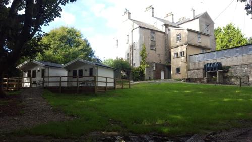 Carrigans的住宿－Dunmore Gardens Log Cabins，一座带栅栏和草地庭院的古老建筑