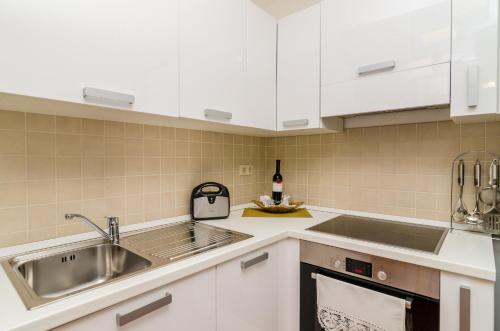 Una cocina con gabinetes blancos y un fregadero. en Apartments Regina Maris, en Klek