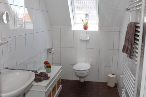 a white bathroom with a toilet and a sink at Haus Deutsche Bucht in Borkum
