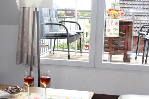 two glasses of wine sitting on a table next to a window at Haus Deutsche Bucht in Borkum