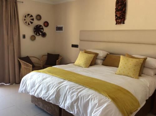 a bedroom with a large white bed with yellow pillows at Damicha Boutique Lodge in Ezulwini