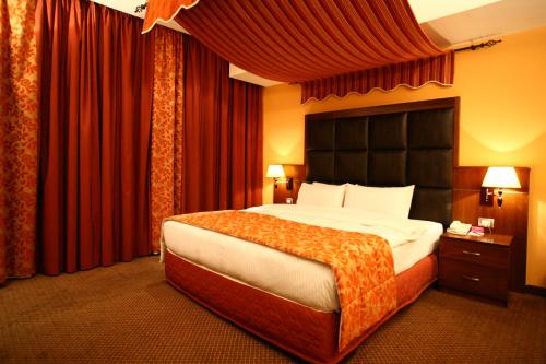 a bedroom with a large bed with red curtains at Markazia Suites in Beirut