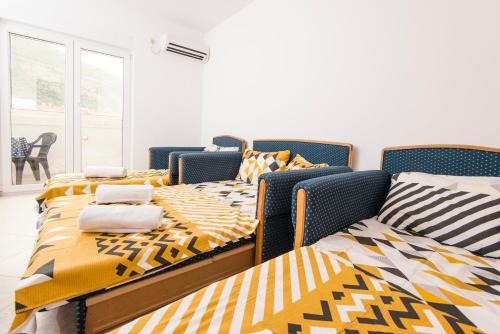 3 camas en una habitación con edredones amarillos y negros en Apartman Budva, en Budva