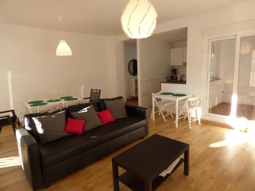 ein Wohnzimmer mit einer schwarzen Couch und einem Tisch in der Unterkunft Viviendas Turísticas La Merced in Ronda