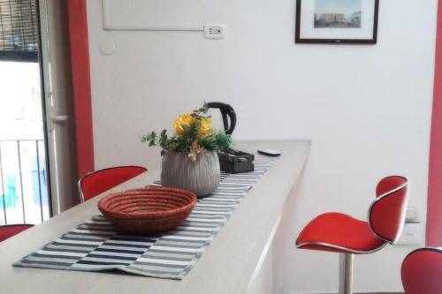une table à manger avec des chaises rouges et un vase de fleurs dans l'établissement Casa Vacanza le Moko', à Naples