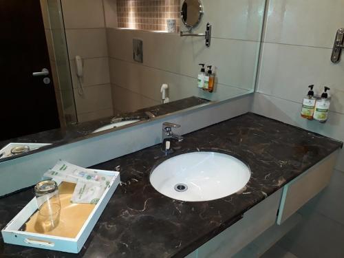 a bathroom counter with a sink and a mirror at Lemon Tree Hotel Candolim in Candolim