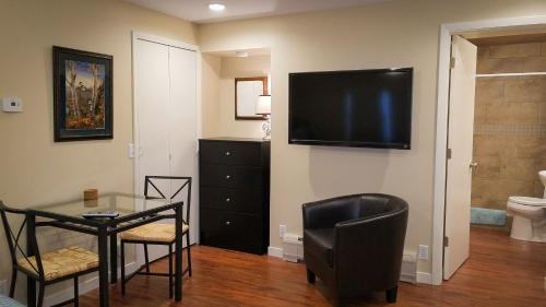 uma sala de estar com uma mesa e uma televisão na parede em HA Whitney Inn em Columbus