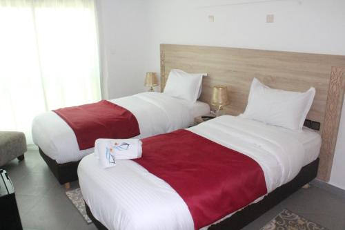 two beds in a hotel room with white and red sheets at Dakhla Sur Mer Hôtel in Dakhla