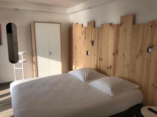a bedroom with a large white bed with wooden walls at Appartement Du Lac in Hossegor