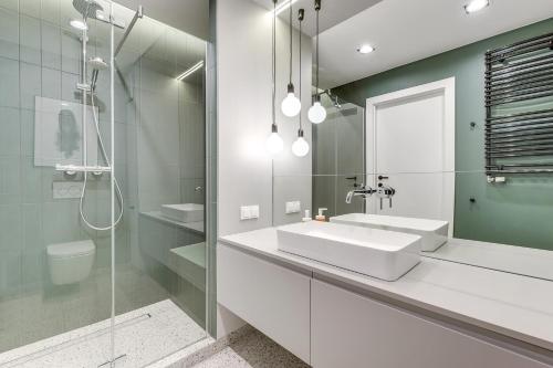 a white bathroom with a sink and a shower at Apartinfo Aura Island in Gdańsk