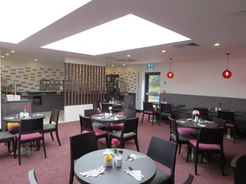 a dining room with tables and chairs and a kitchen at Ramada Bristol West in Easton in Gordano