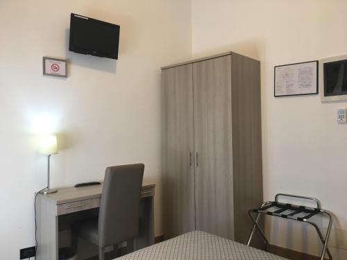 a bedroom with a desk with a computer and a cabinet at Hotel Chopin in Genoa