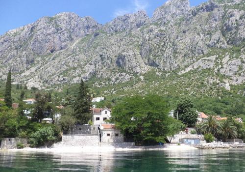 un pueblo en el agua con montañas en el fondo en House on the beach en Kotor
