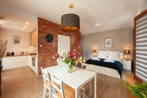 クラクフにあるBrowar Lubicz Residenceのベッドと花が飾られたテーブルのある寝室
