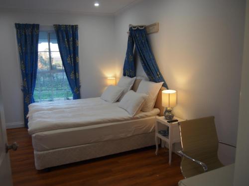 a bedroom with a bed with blue curtains and a window at 1837 Barossa Luxury Vineyard Cottages in Lyndoch