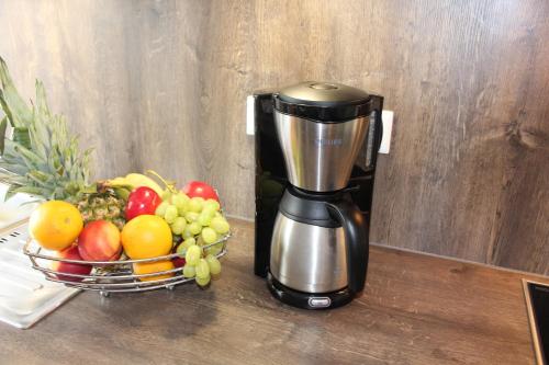 a coffee maker sitting next to a bowl of fruit at Haus Deutsche Bucht in Borkum