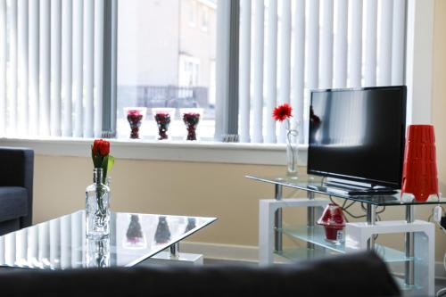 a living room with a glass table with a television at Netherton House in Wishaw