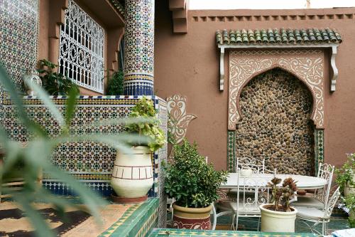 a patio with a table and potted plants on a building at Riad Ouarzazate in Ouarzazate