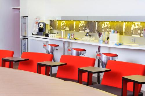 a dining room with red chairs and a counter at Novotel Paris Rueil Malmaison in Rueil-Malmaison