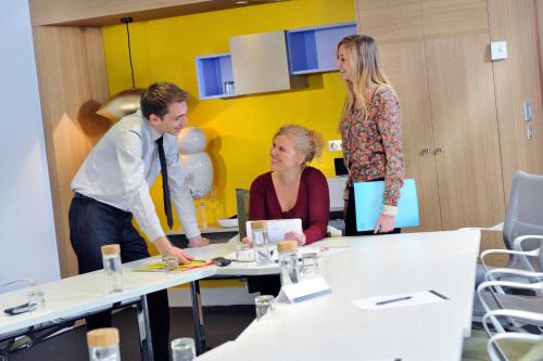 a man and two women standing in an office at Novotel Paris Rueil Malmaison in Rueil-Malmaison