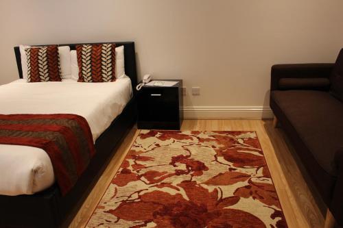 a bedroom with a bed and a couch and a rug at Westpoint Hotel in London