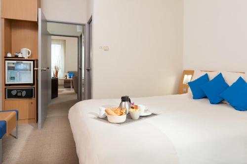 a large white bed with two bowls of food on it at Novotel Paris Rueil Malmaison in Rueil-Malmaison