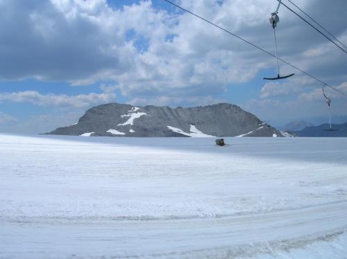 a ski lift over a snow covered field with a mountain at Hotel Genziana in Passo Stelvio