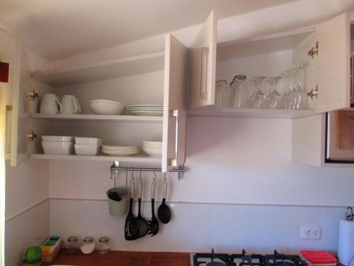 a kitchen with white cabinets and plates and utensils at Quinua Boutique Apartments in Cusco