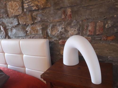 a white lamp on a table next to a brick wall at Casa In Piazza in Cividale del Friuli