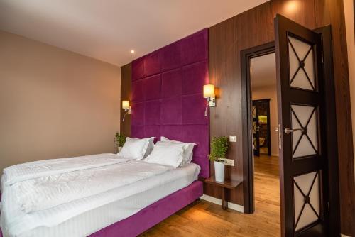 a bedroom with a large bed with a purple wall at F&B Spa Resort (ex. Fomich Hotel) in Bukovel