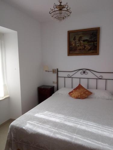 a bedroom with a white bed with a chandelier at Casa Rural Mimbrero in Aldeadávila de la Ribera
