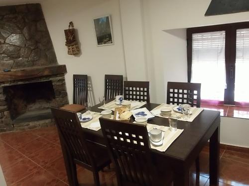 Casa Rural Los Robles في فالفرد دو لوس أرويوس: غرفة طعام مع طاولة مع كراسي ومدفأة