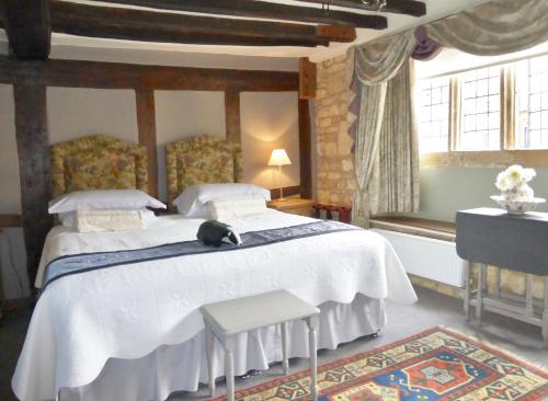 a bedroom with a bed with a cat sitting on it at Badgers Hall in Chipping Campden