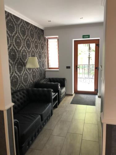 a waiting room with black leather couches and a door at Tardosi Vendégház in Miskolctapolca