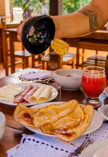 uma pessoa a deitar vinho num prato de comida numa mesa em Pousada Carioca - Pousada de Charme em Jericoacoara