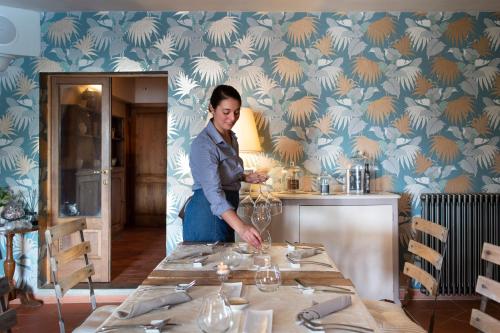 a woman standing in front of a table with wine glasses at Borgo I Vicelli Adults Only Relais in Bagno a Ripoli