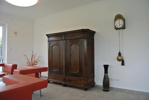 a wooden cabinet in a room with a clock on the wall at Penthousewohnung in Mettmann