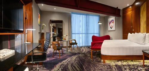グアダラハラにあるHard Rock Hotel Guadalajaraのベッドと赤い椅子が備わるホテルルームです。